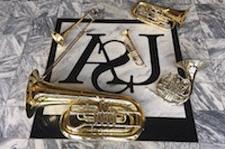 Pictured is the USA Logo on the marble floor of the Laidlaw Performing Arts Center Lobby.  Brass instruments are placed strategically and artistically around the logo.