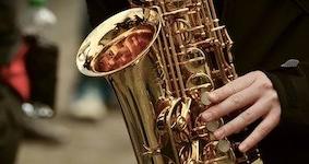 Pictured is an alto saxophone being played by an anonymous performer.